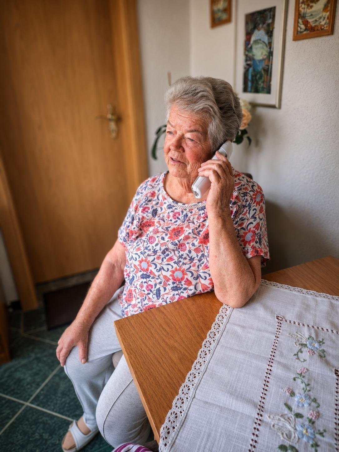 Eine Seniorin telefoniert zuhause